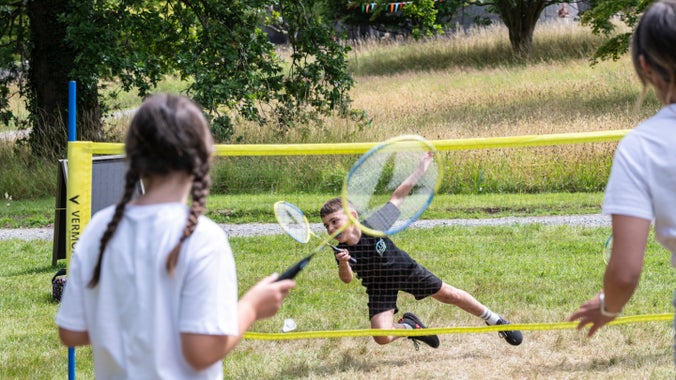 A family enjoy playing badminton on the lawn at Penrhyn Castle during the Summer of Play